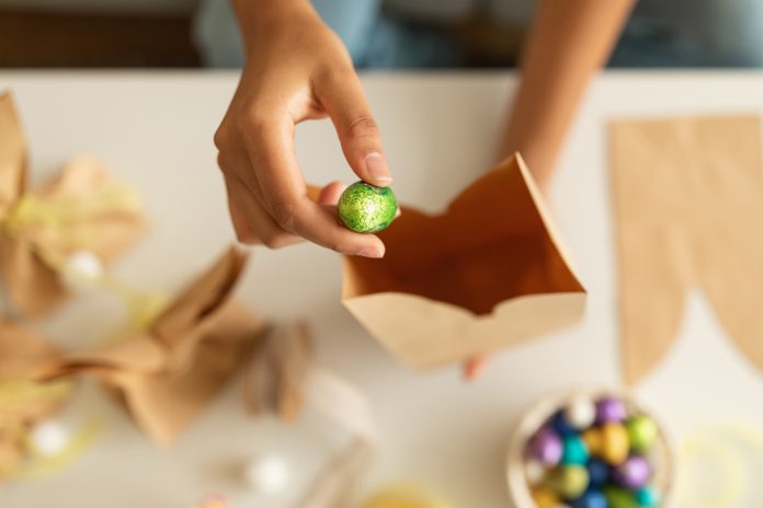 Festive Treat. Unrecognizable Woman Putting Chocolate Egg Into Paper Craft Bag At Home